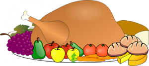 picture of a cooked turkey with apples, carrots, grapes, bread, cheese, and tomatoes around it